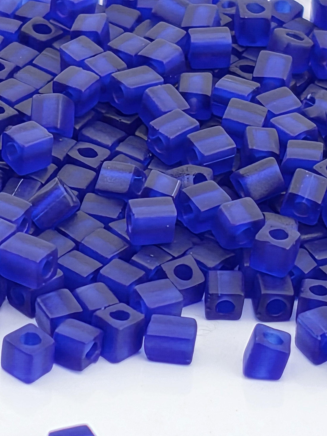 The image is a close-up of numerous blue cubes or blocks, likely made of a material like plastic or glass. The cubes are of various sizes and shapes, creating a visually interesting and diverse arrangement.
