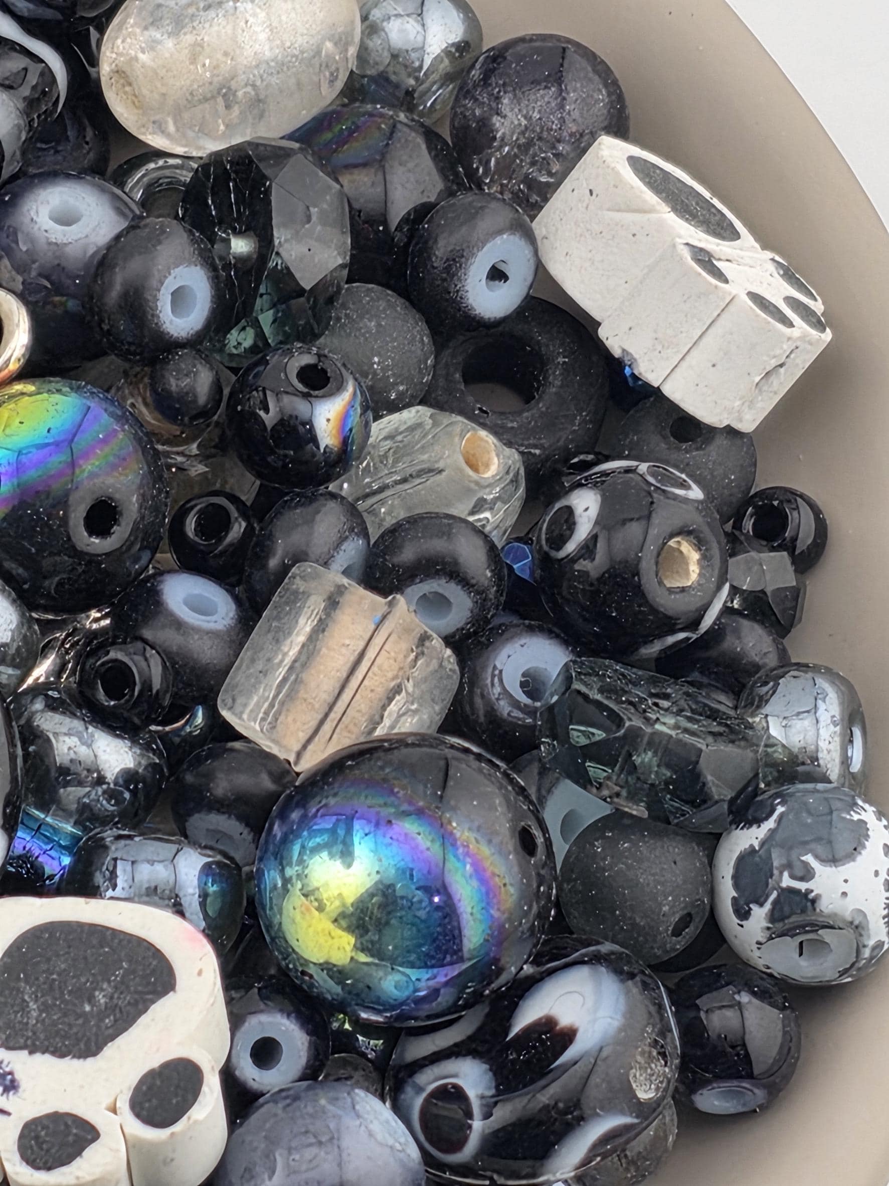 A bowl filled with various beads, including black, white, and multicolored beads, creating a visually striking and diverse collection.