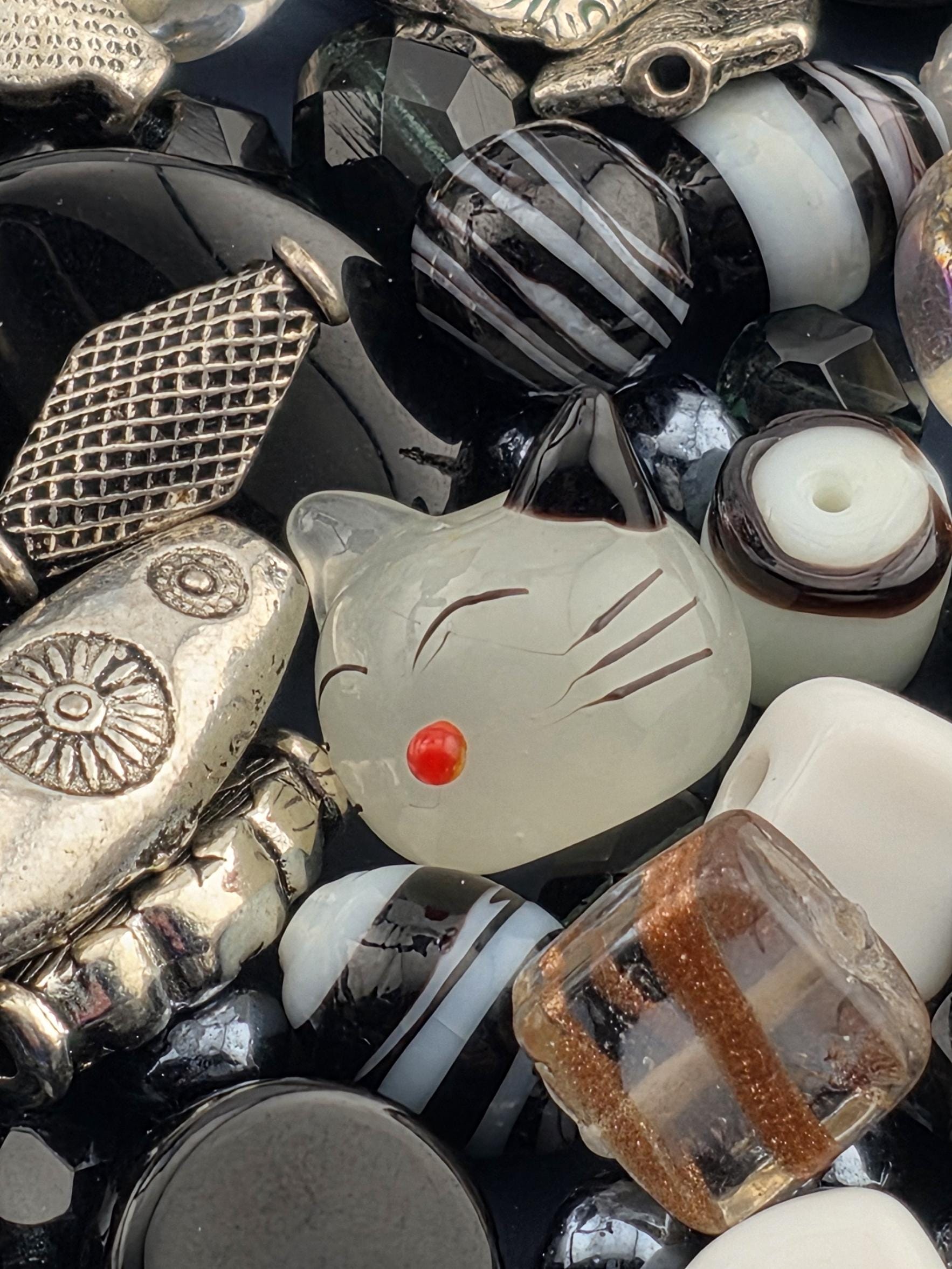 a variety of beads and metal objects, including glass beads, metal beads, and other decorative items, arranged in a visually appealing manner.