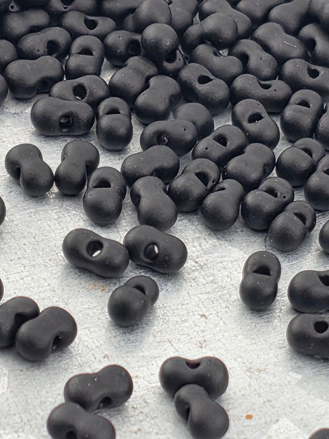a collection of black beads or objects scattered on a white surface.