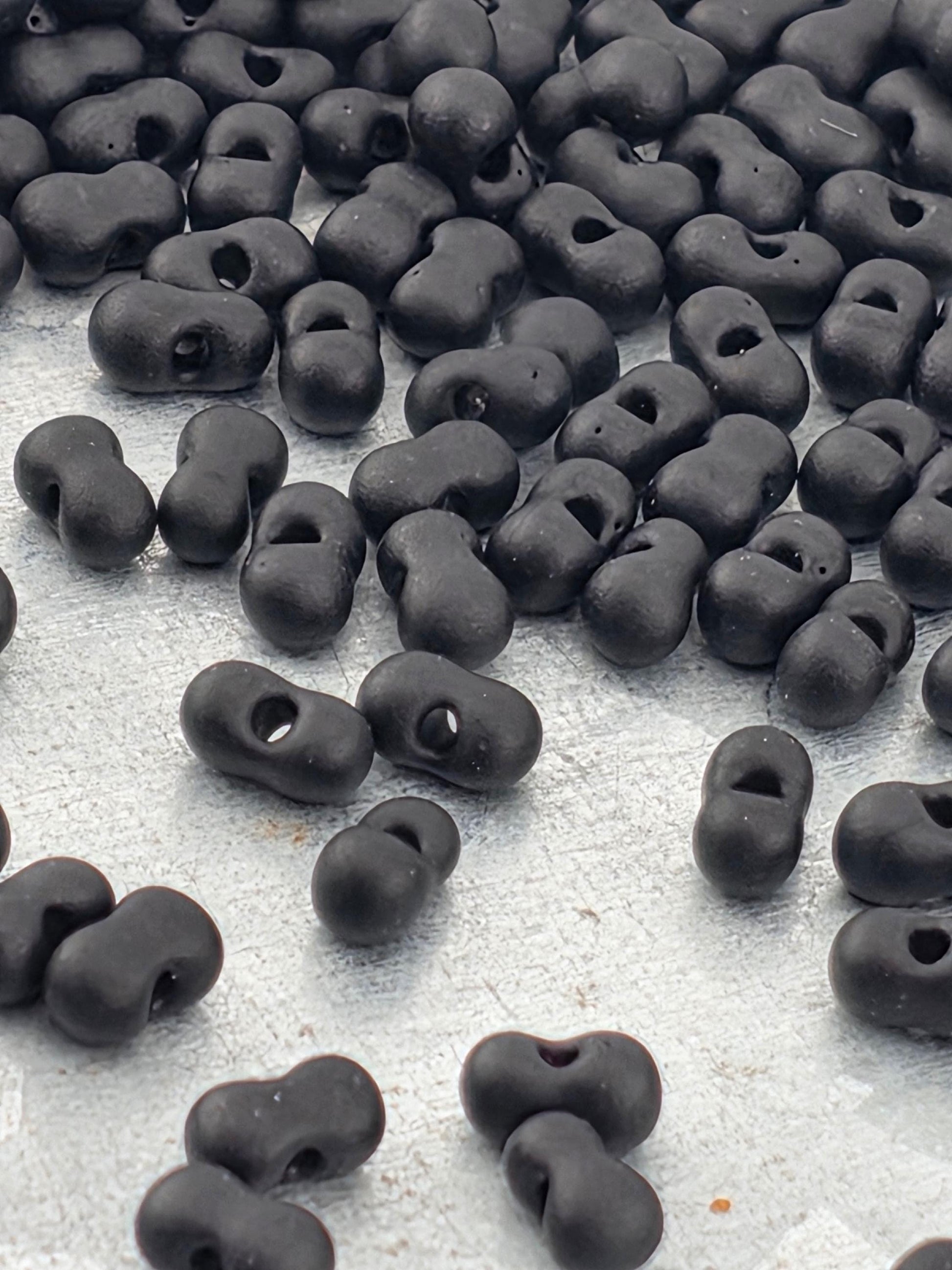 a collection of black beads or objects scattered on a white surface.