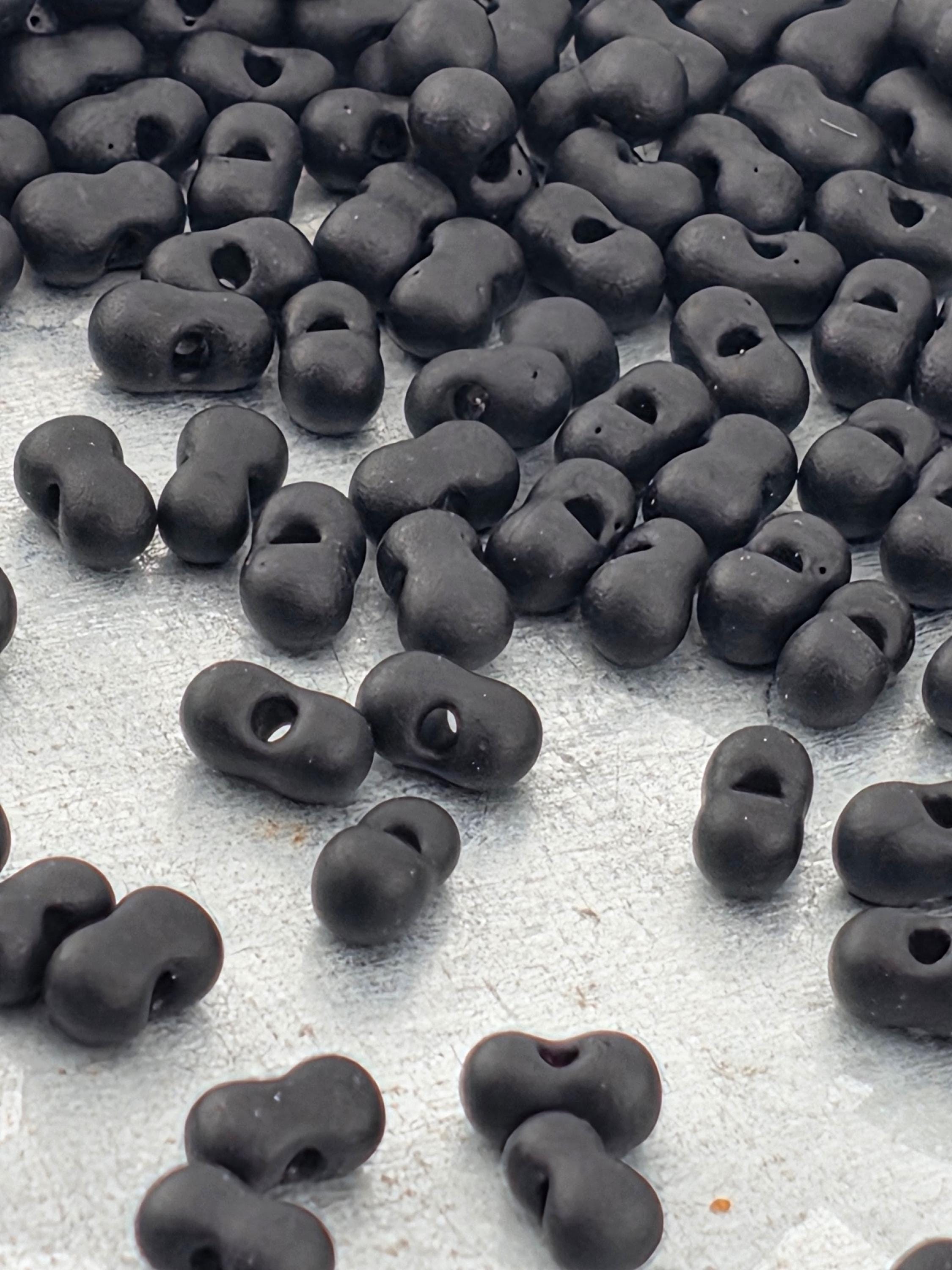 a collection of black beads or objects scattered on a white surface.