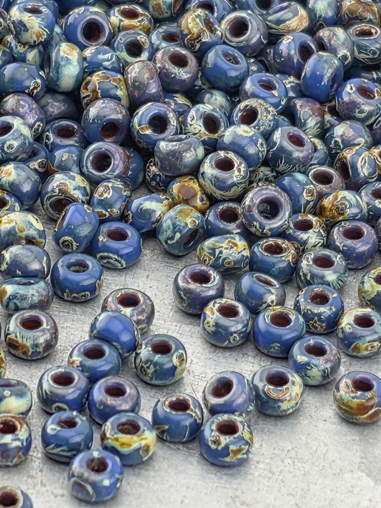 a large pile of blue and brown beads scattered on a surface.