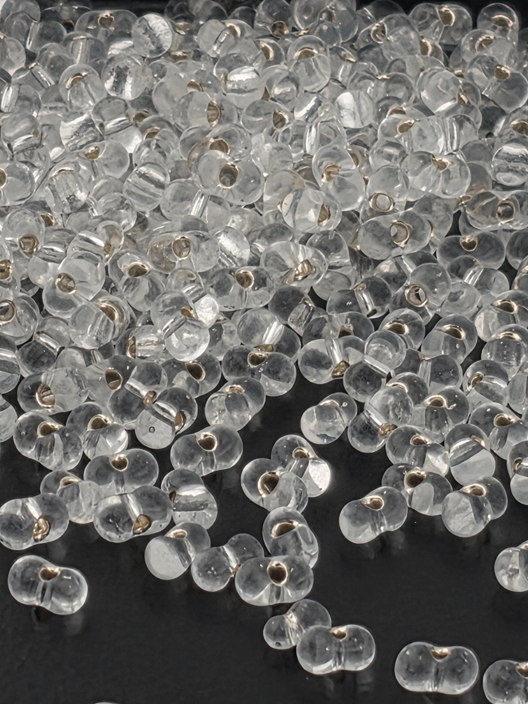 a close-up view of numerous clear glass beads scattered on a dark background.