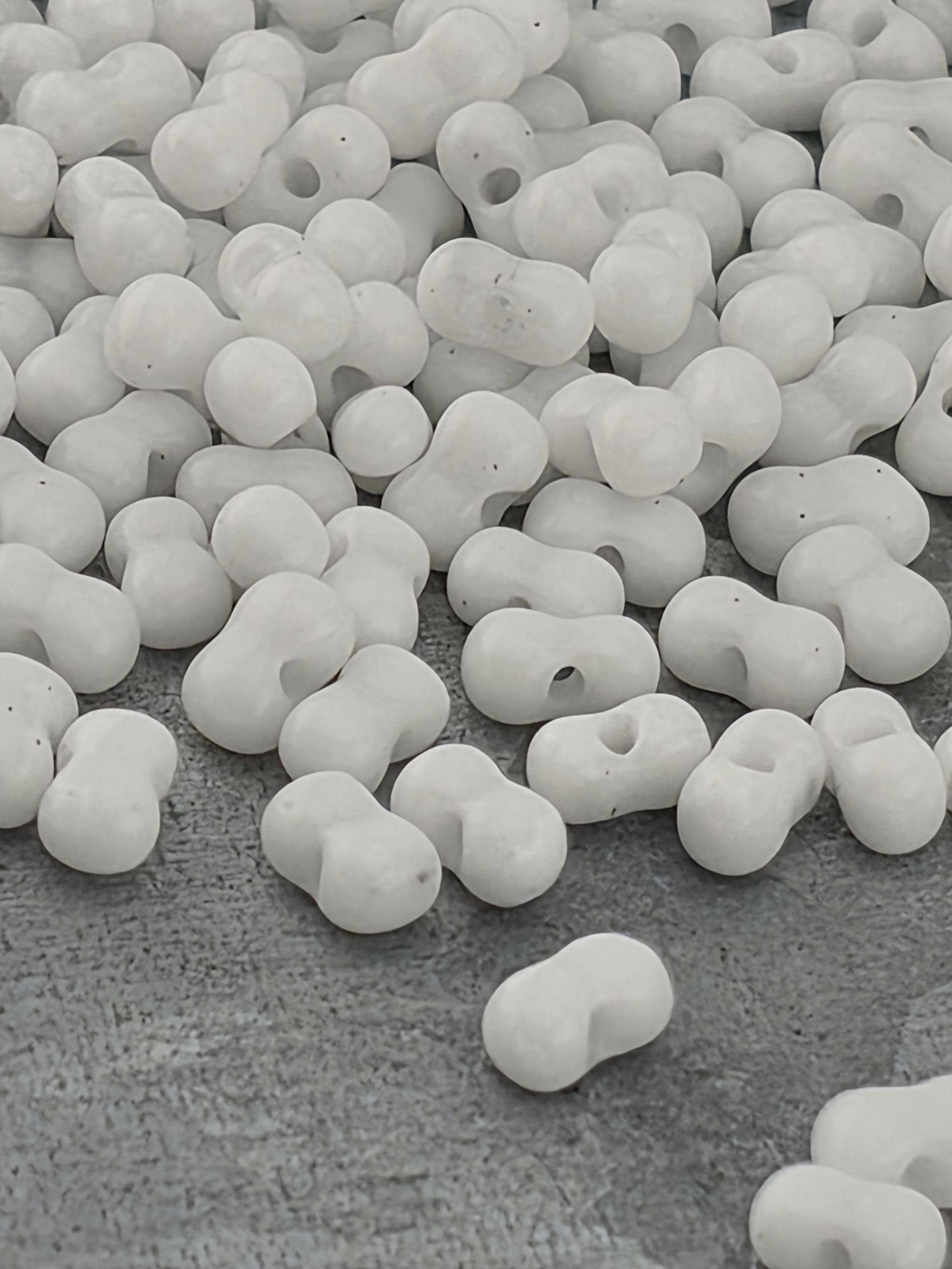 numerous white, spherical objects scattered across a textured gray surface.