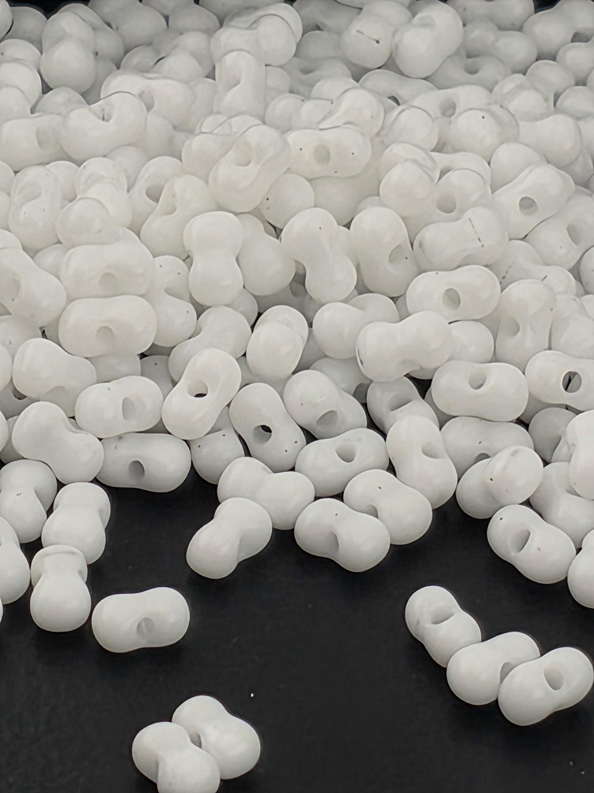 a large pile of white beads or beads, scattered on a black surface.
