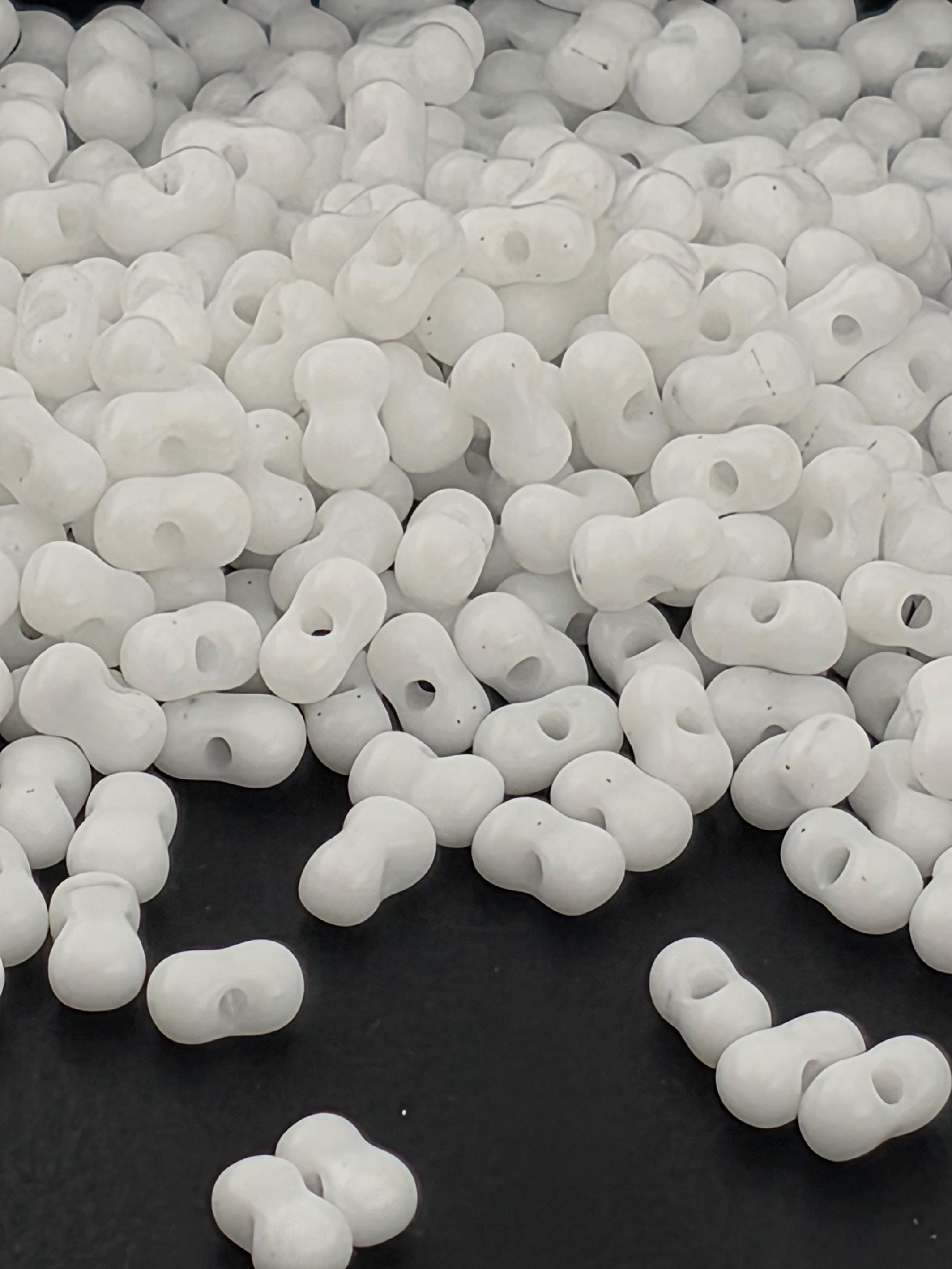 a large pile of white beads or beads, scattered on a black surface.