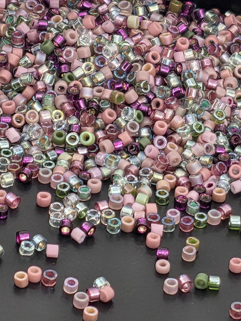 A pile of multicolored beads, including clear, pink, green, and purple, scattered on a dark surface.