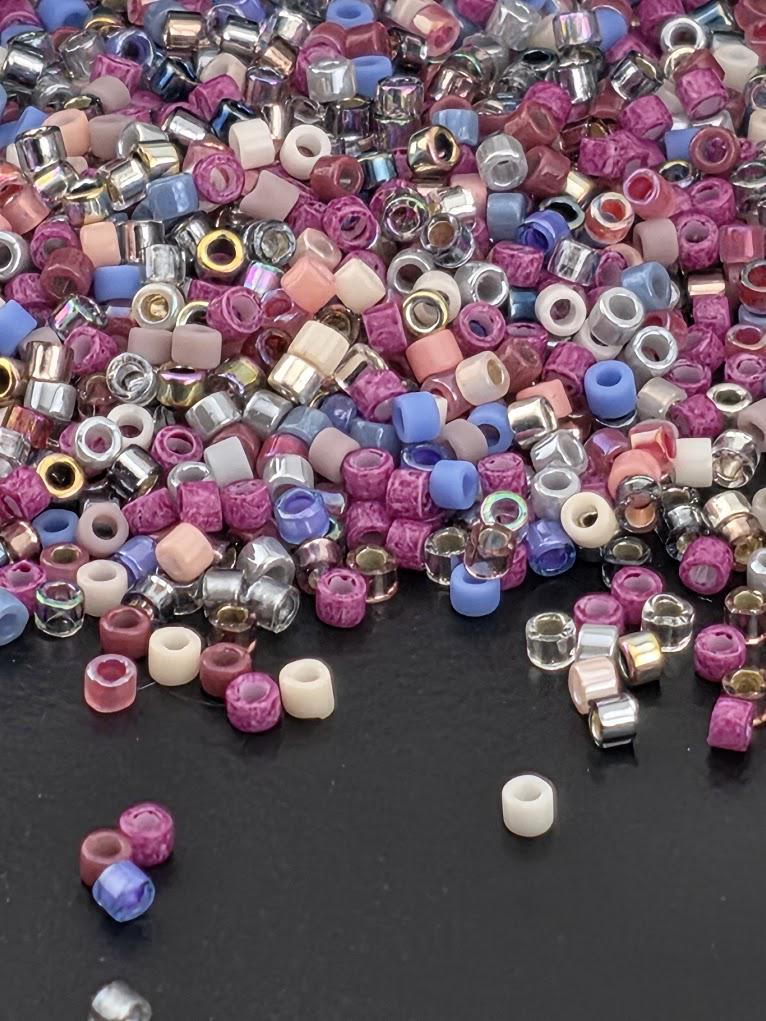 A pile of multicolored beads, including clear and colored beads, scattered on a dark surface.
