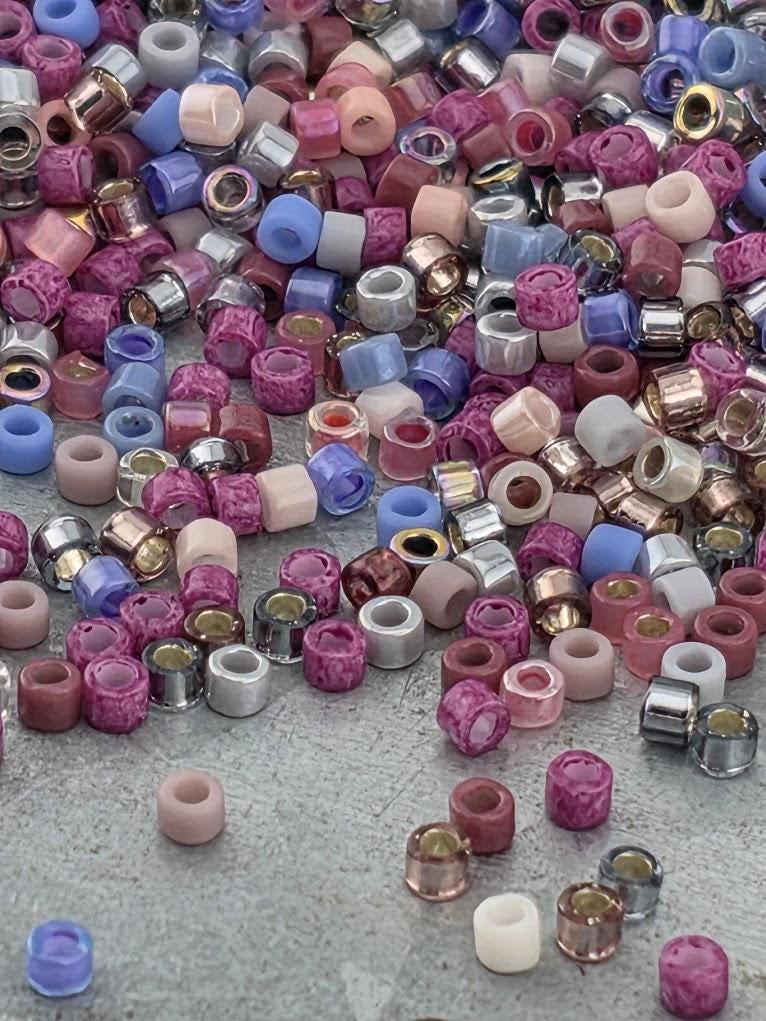 A colorful pile of various beads, including multicolored glass beads and metal beads, scattered on a surface.