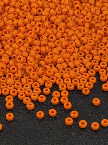 a close-up view of numerous orange beads scattered on a dark surface, creating a visually striking contrast.