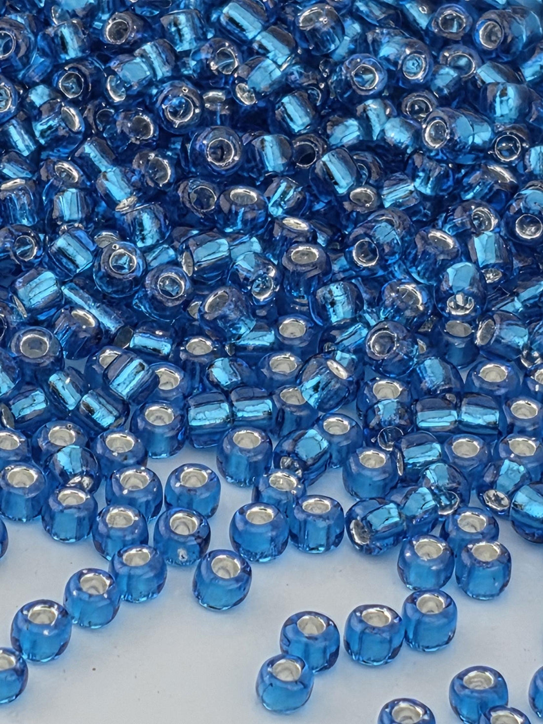 The image is a close-up of numerous blue and white beads, possibly made of glass or plastic, scattered and overlapping each other.