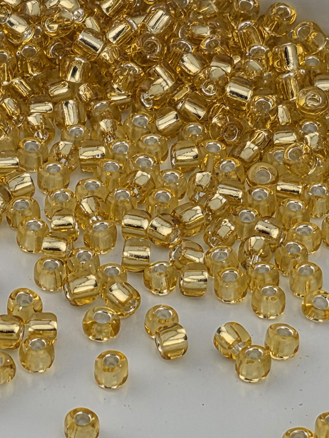 a close-up view of numerous small, clear glass beads in a golden color, scattered across a surface.