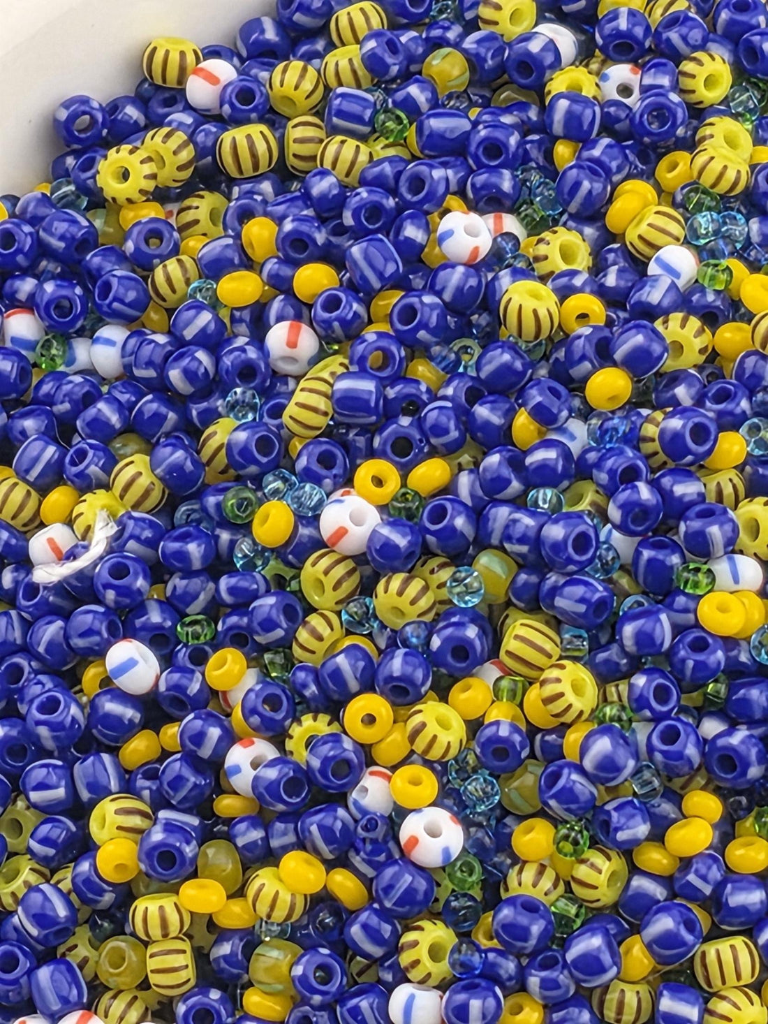 A colorful assortment of beads in various shapes and sizes, including blue, yellow, and multicolored beads, creating a vibrant and playful visual.