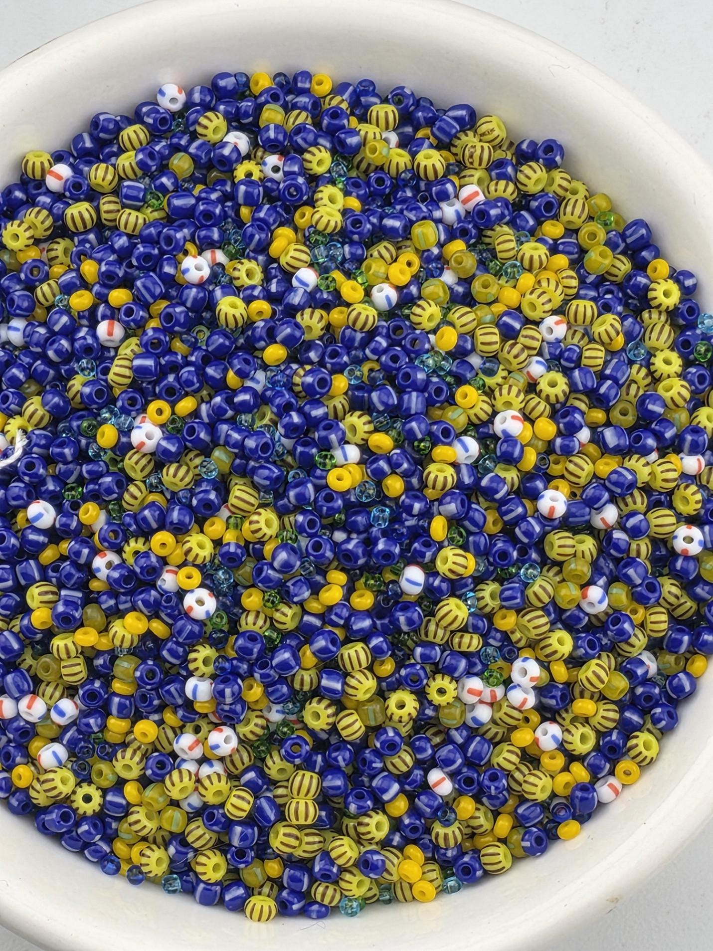 A bowl filled with colorful beads in various shades of blue, yellow, and white.