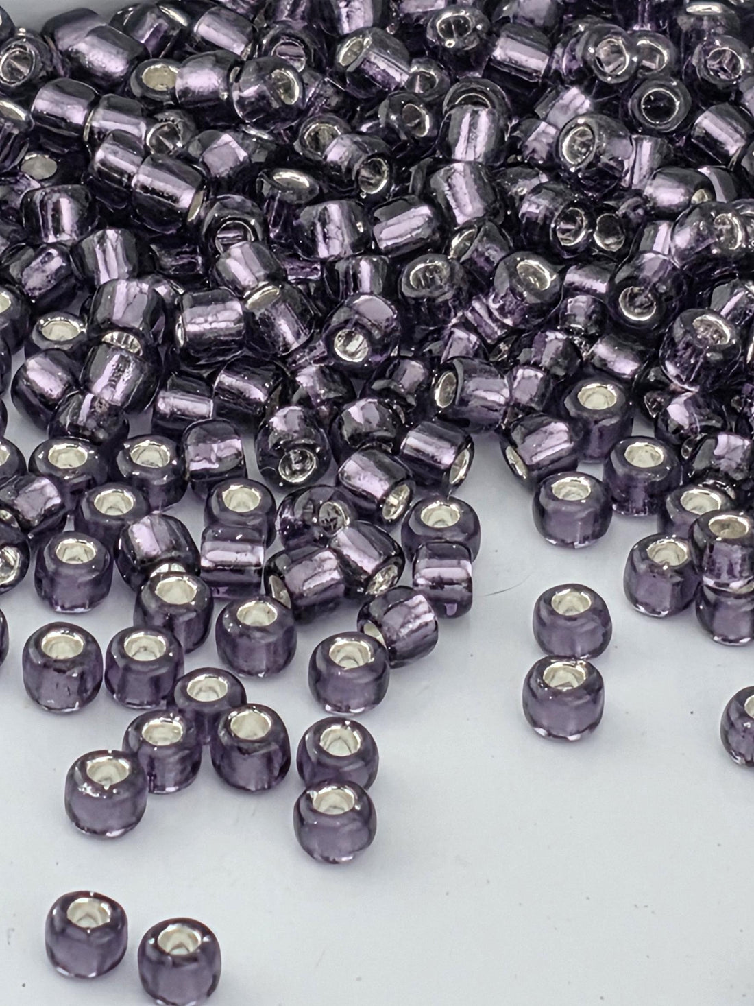 A close-up image of numerous purple glass beads scattered on a white surface.