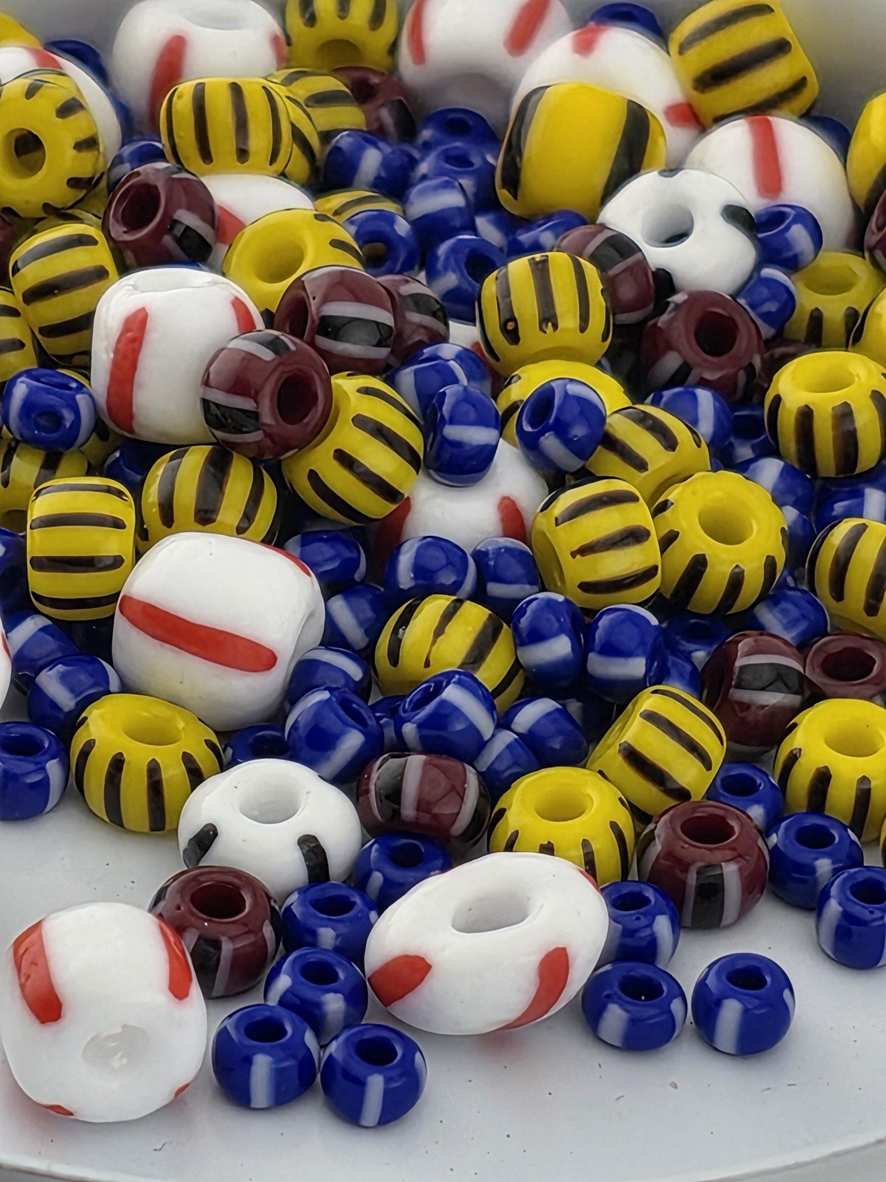 A colorful assortment of beads in various shapes and sizes, including yellow, blue, red, and white beads, scattered on a surface.