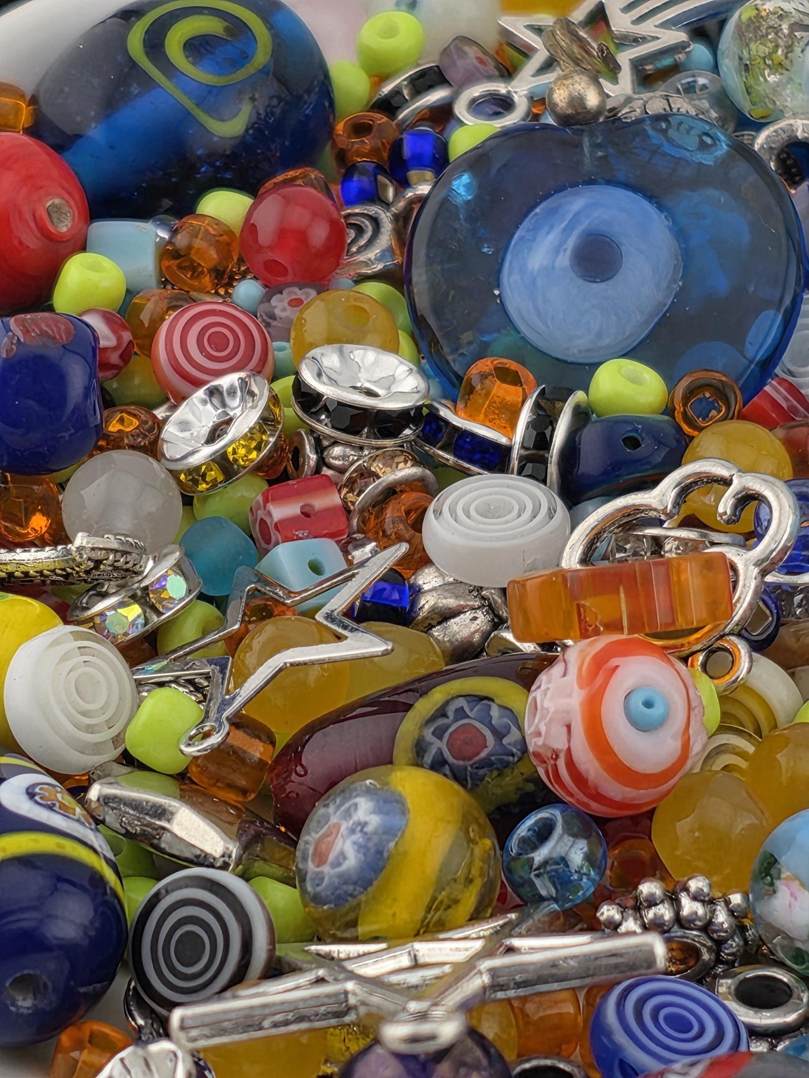 A colorful assortment of beads, charms, and other decorative items, including glass beads, metal charms, and other small objects, creating a visually appealing and diverse collection.