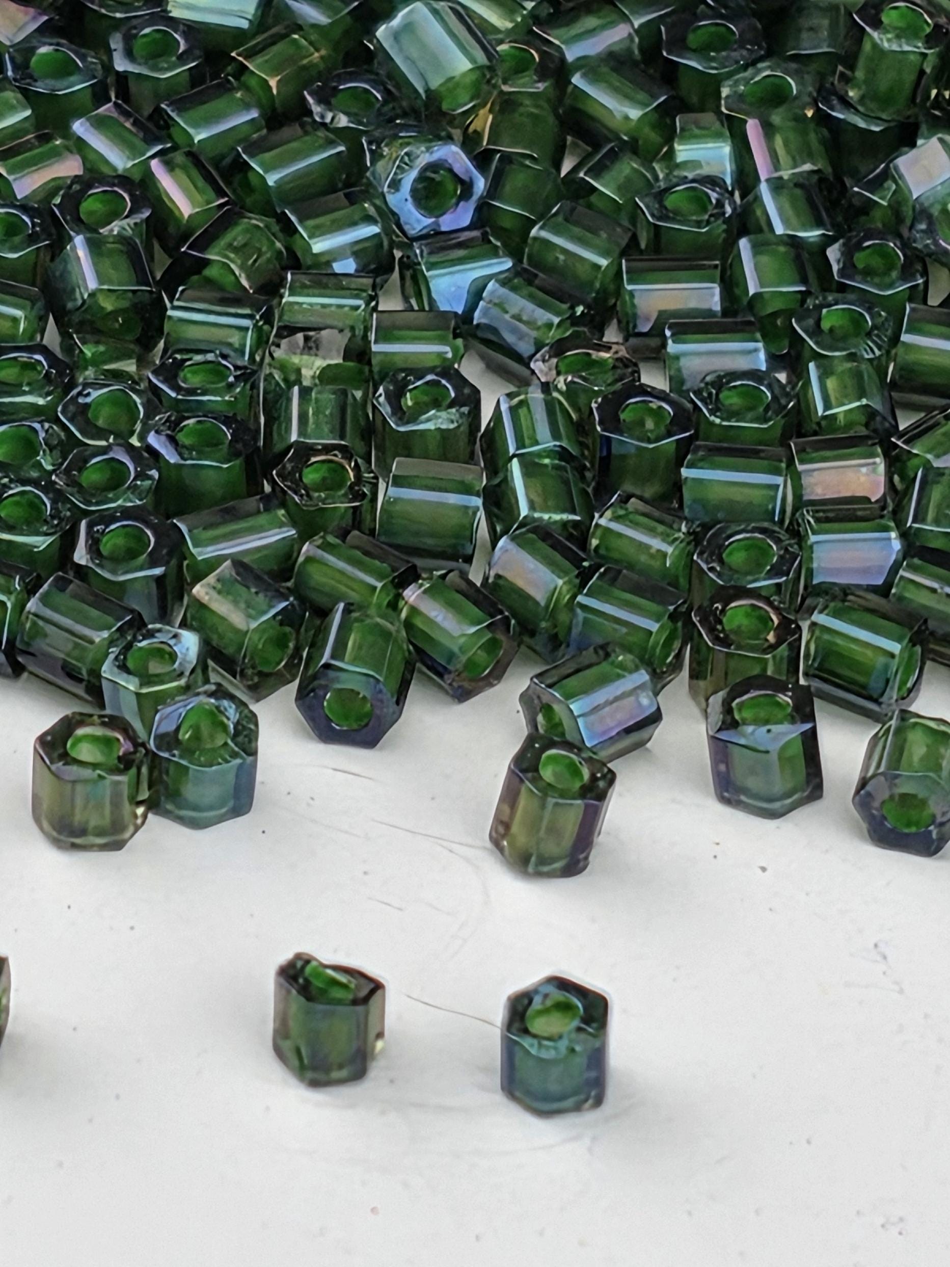 a close-up view of numerous green glass beads scattered on a white surface.