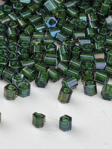 a close-up view of numerous green glass beads scattered on a white surface.
