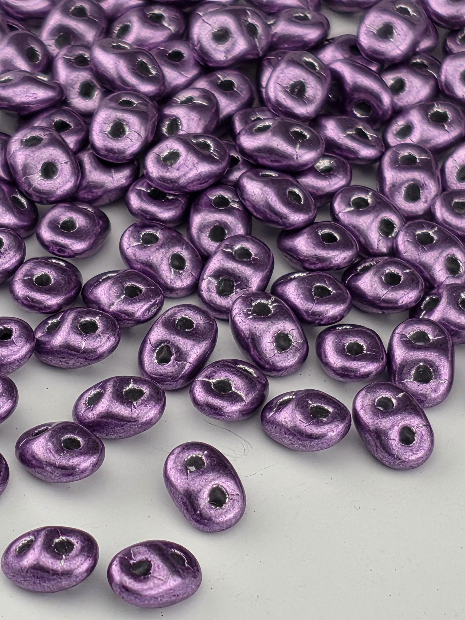 a collection of purple beads scattered across a white background.