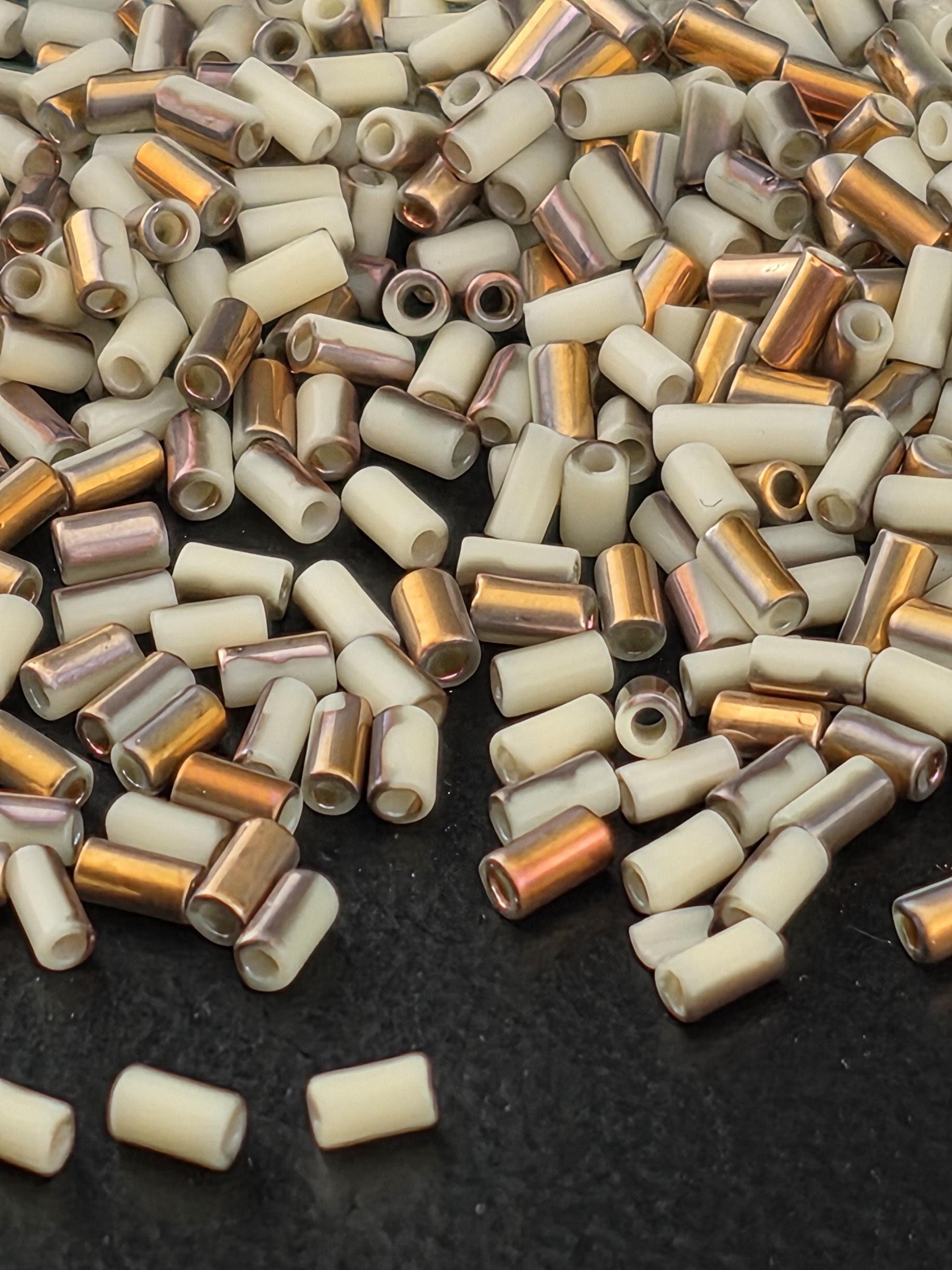 a close-up view of a pile of small, white and gold beads scattered on a dark surface.
