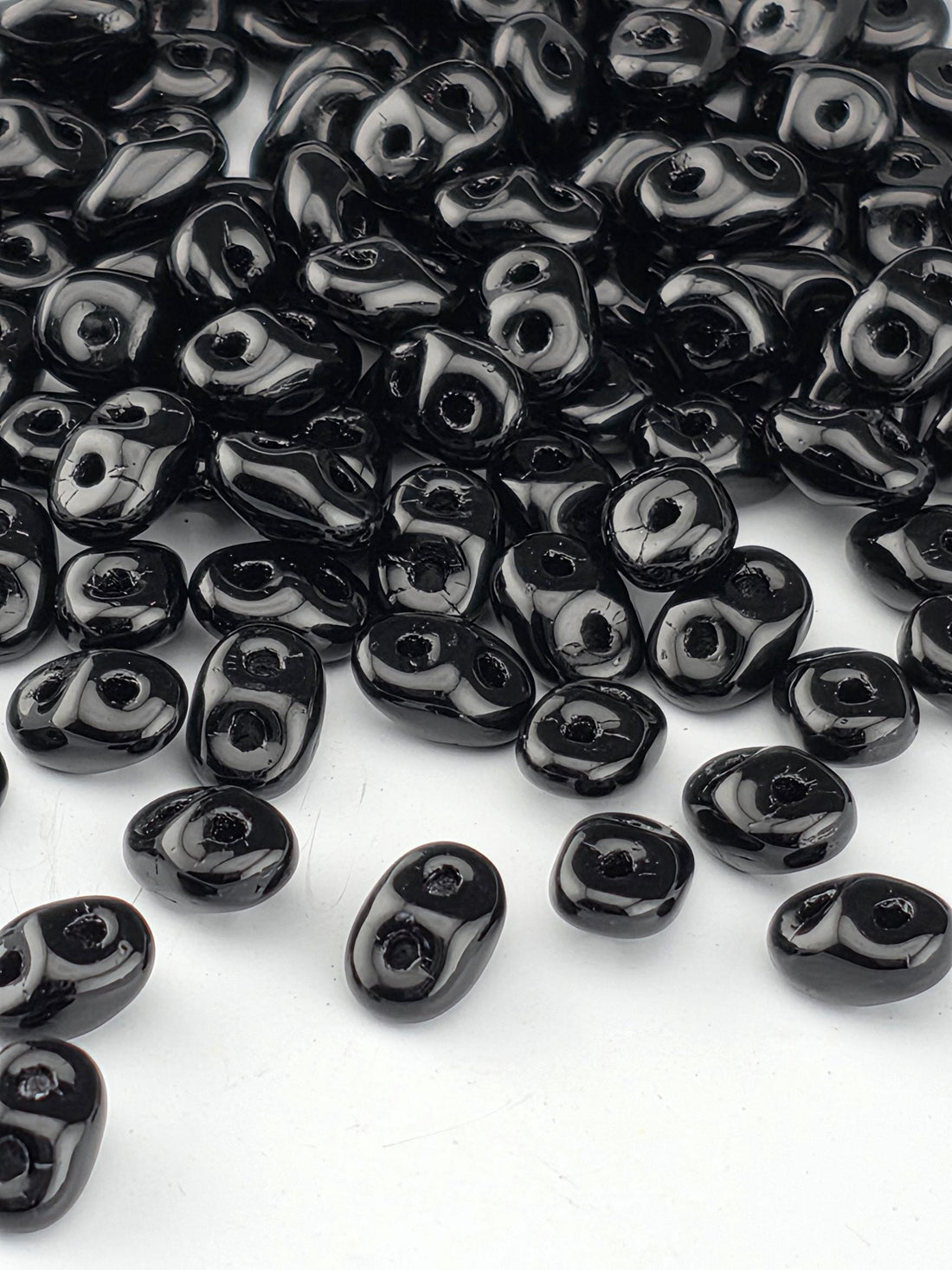 a collection of black beads scattered on a white background.
