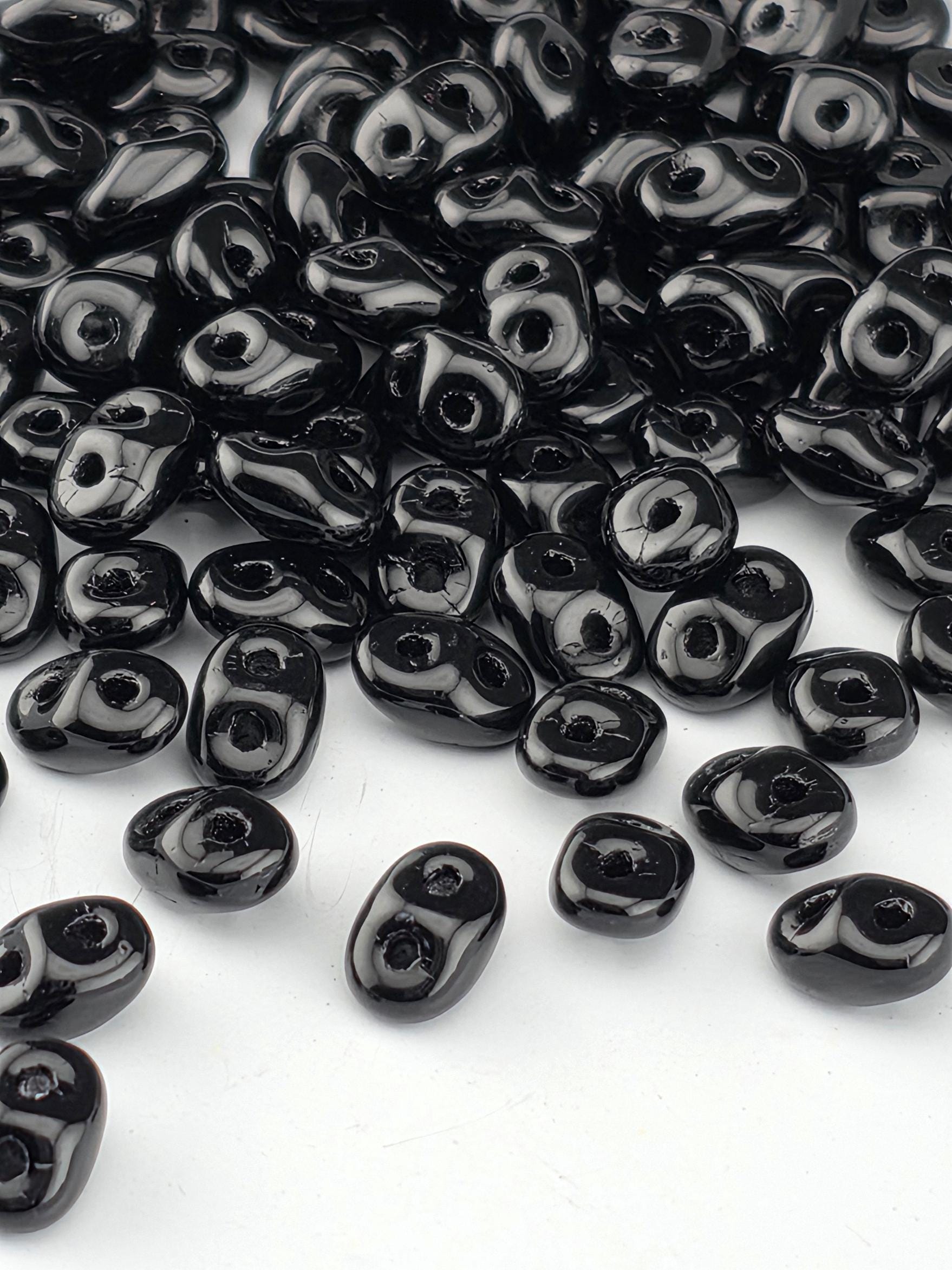 a collection of black beads scattered on a white background.