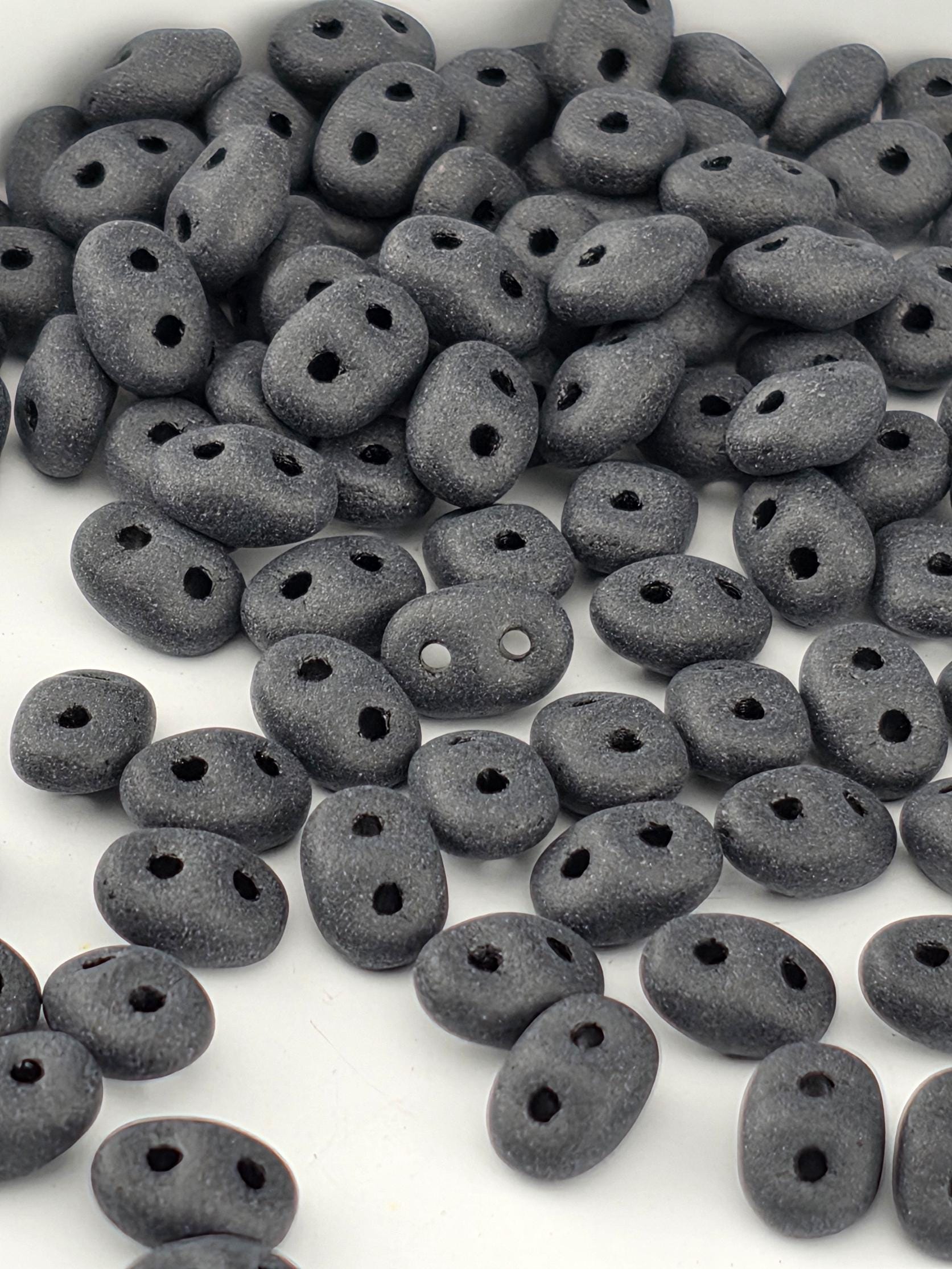 a collection of small, black beads scattered on a white surface.