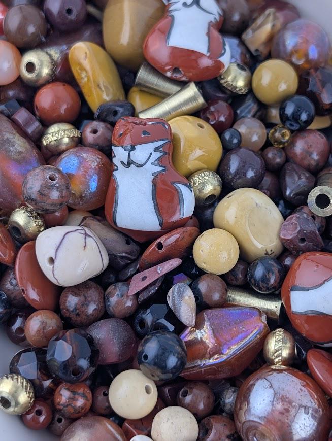 The image is a close-up of a variety of colorful beads and beads, including glass beads, metal beads, and other materials, arranged in a visually appealing manner.