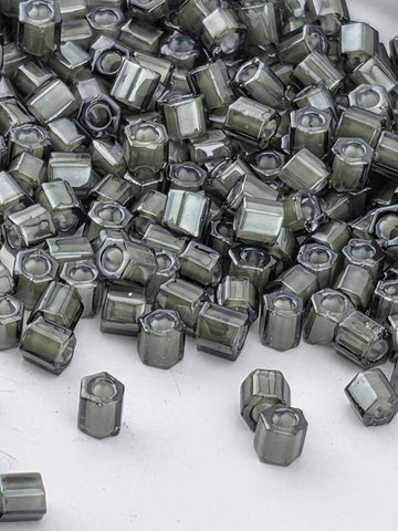 a large pile of small, square-shaped objects with a dark gray or black color, scattered on a white surface.