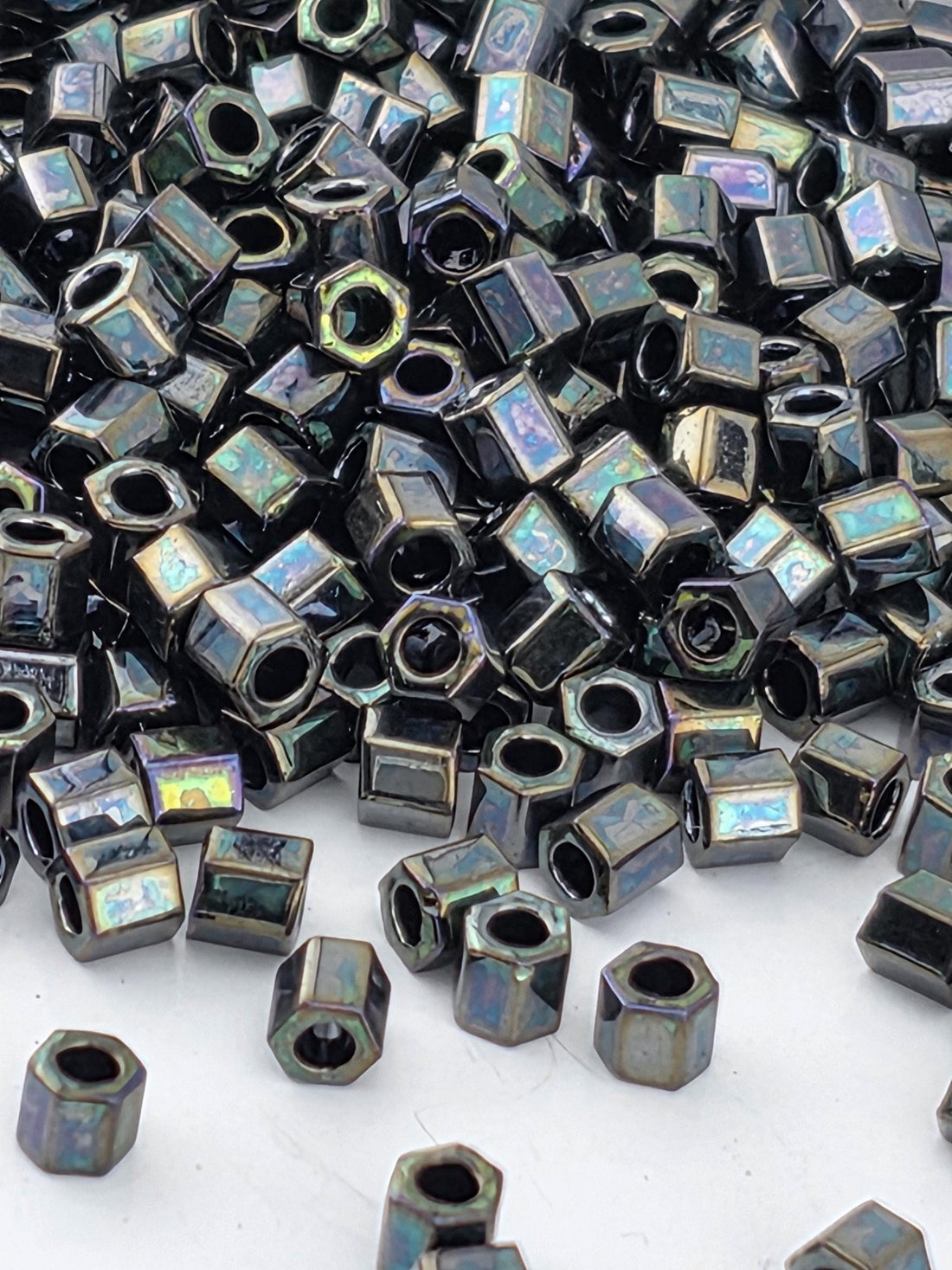 a close-up view of numerous black hexagonal nuts or bolts scattered across a white surface.