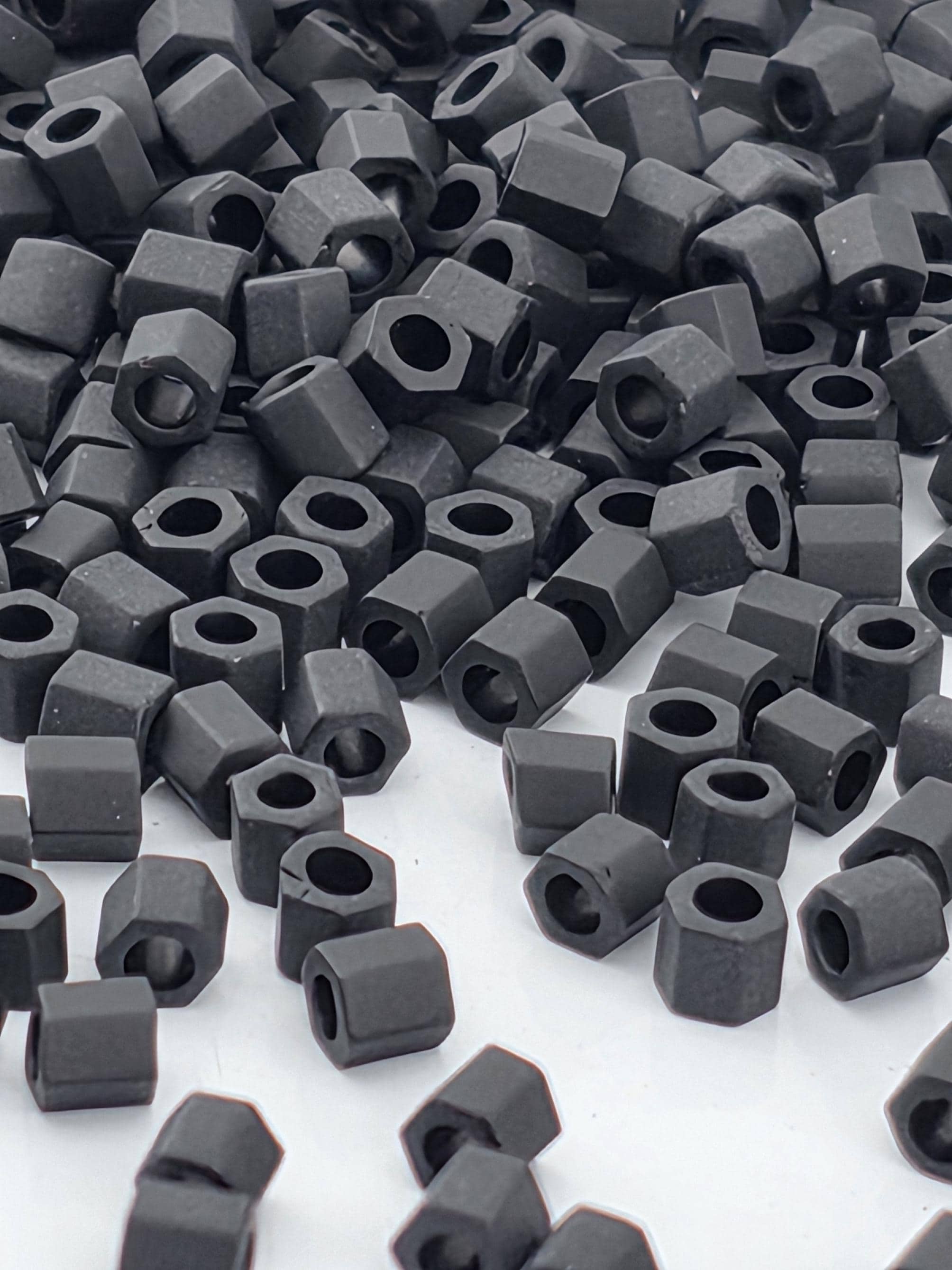 numerous black hexagonal nuts or bolts scattered across a white background.