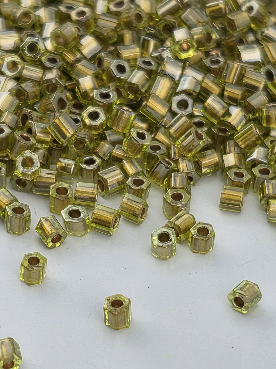 a close-up view of numerous small, hexagonal-shaped objects in various shades of green, scattered across a white surface.