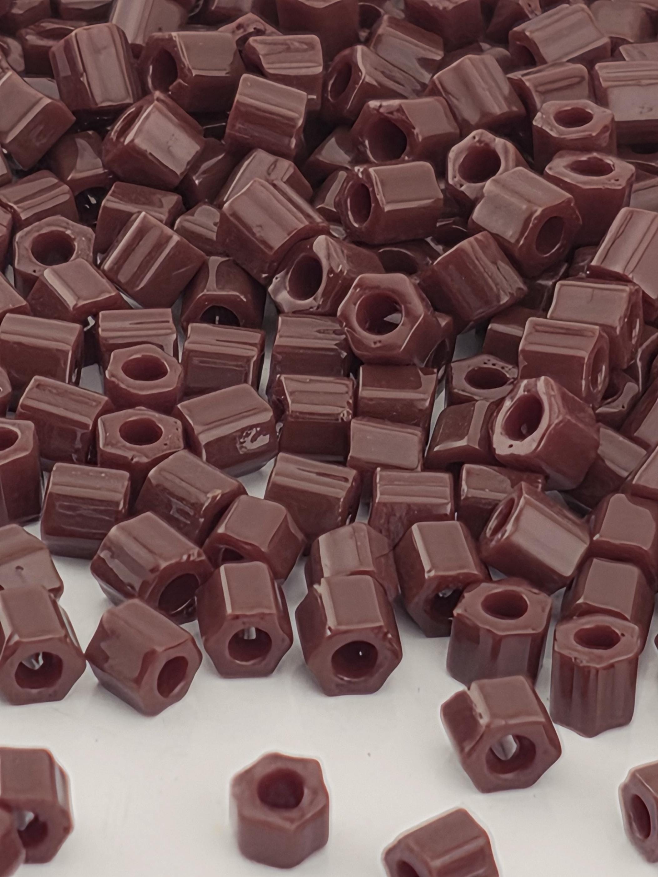 a close-up view of a pile of brown, square-shaped objects, which appear to be small, rectangular-shaped items. The objects are scattered and overlapping, creating a visually interesting and textured composition.