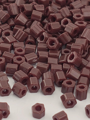 a close-up view of a pile of brown, square-shaped objects, which appear to be small, rectangular-shaped items. The objects are scattered and overlapping, creating a visually interesting and textured composition.