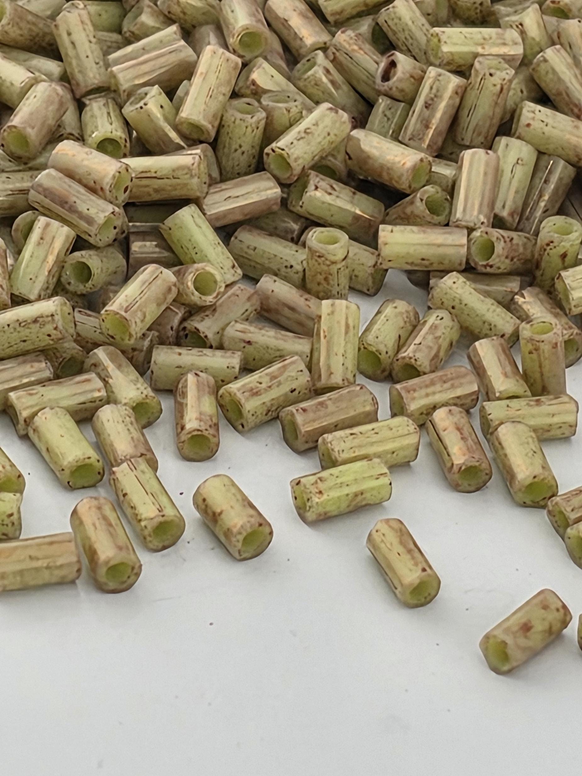 a pile of small, cylindrical objects with a speckled or speckled appearance, scattered on a white surface.