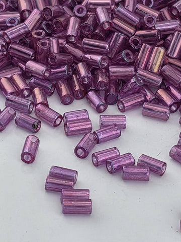 a close-up view of numerous small, purple beads scattered across a white surface.