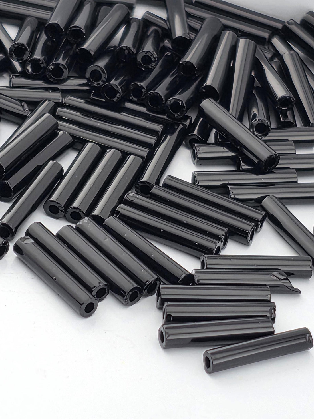 numerous black cylindrical objects, possibly metal rods or tubes, scattered across a white background.