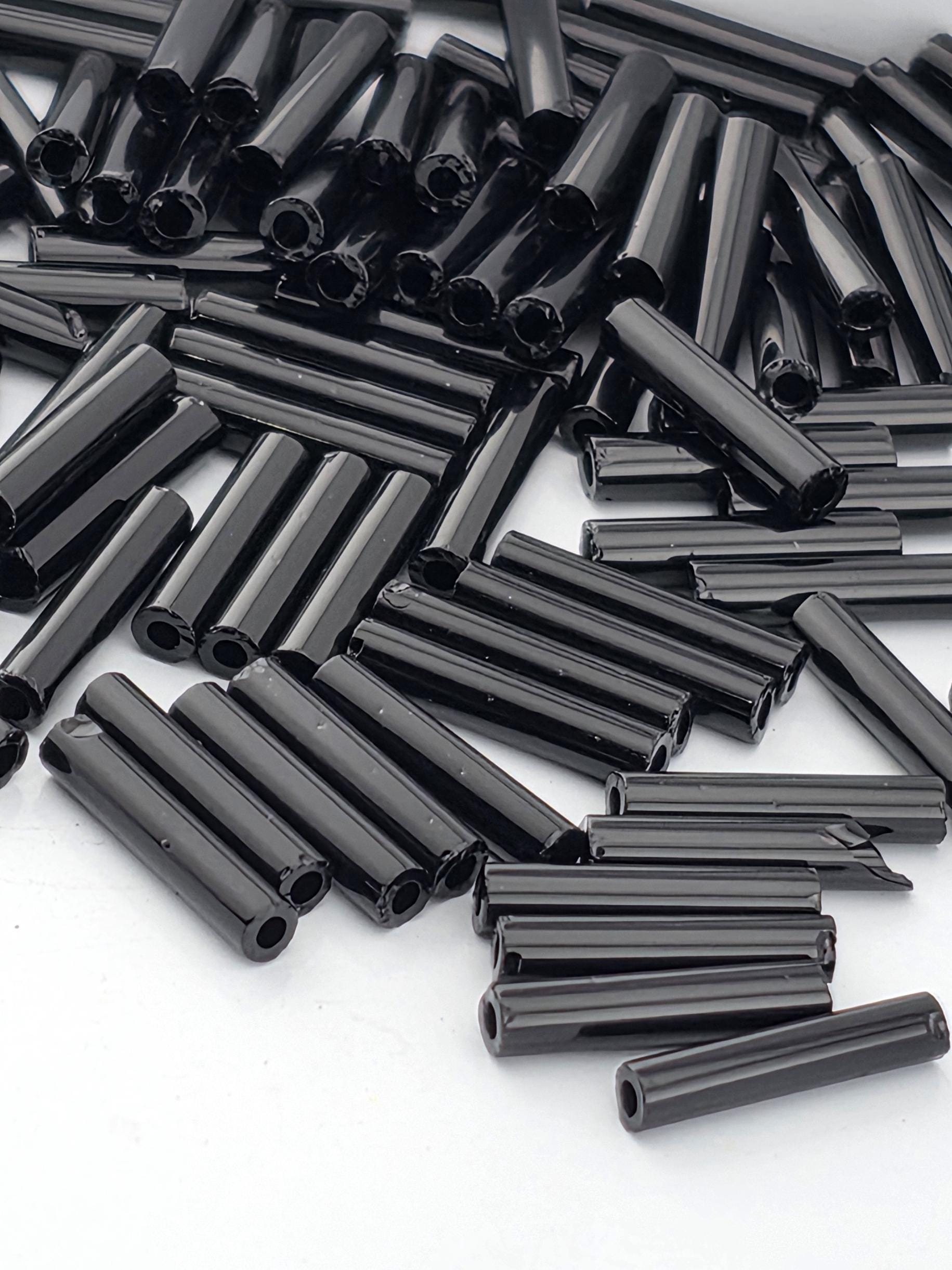 numerous black cylindrical objects, possibly metal rods or tubes, scattered across a white background.