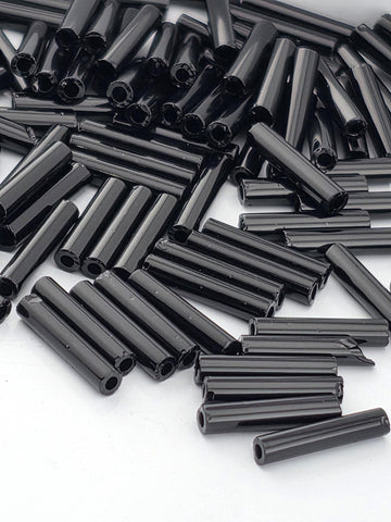 numerous black cylindrical objects, possibly metal rods or tubes, scattered across a white background.