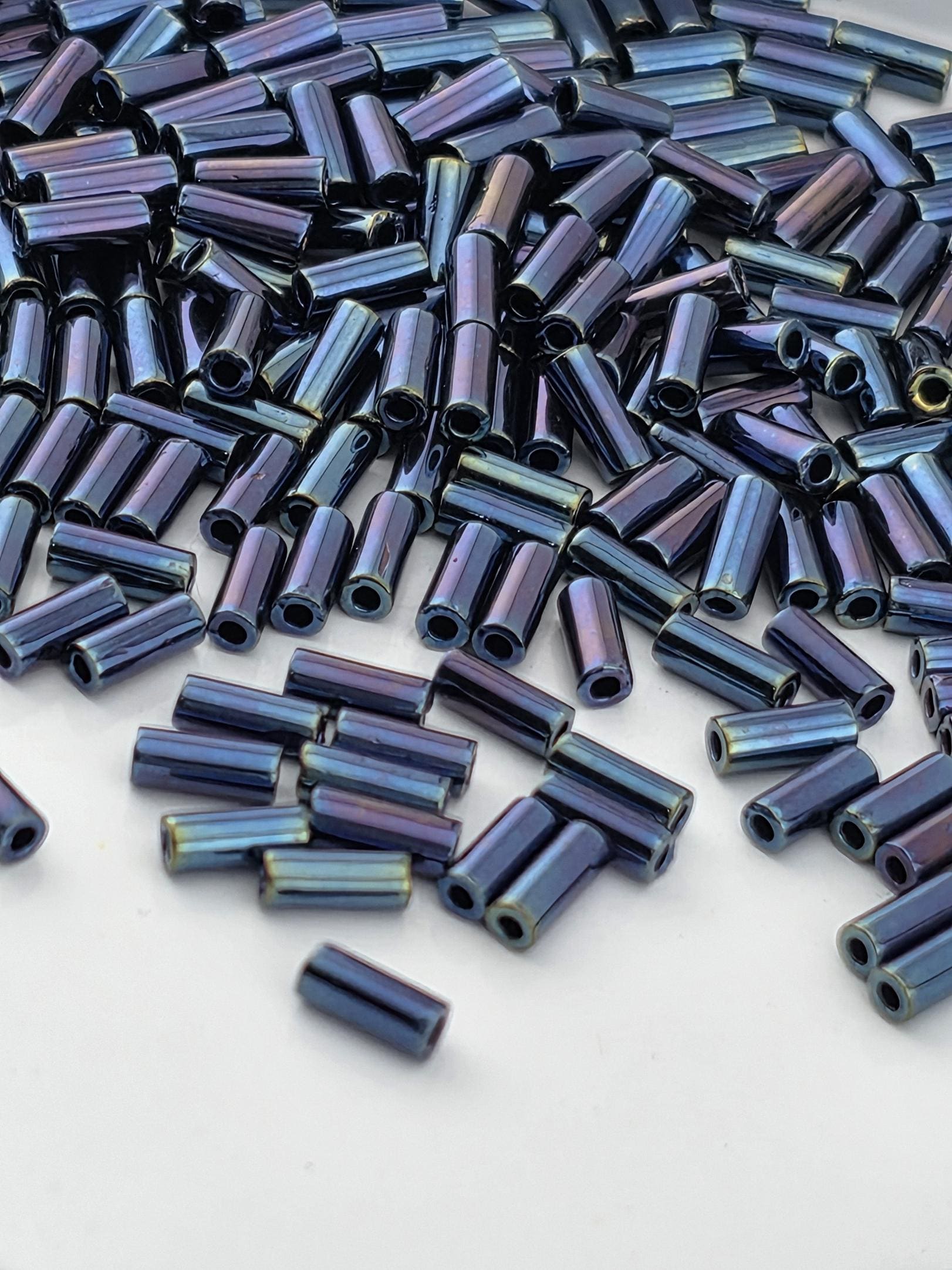 a large pile of blue and purple beads scattered on a white surface.