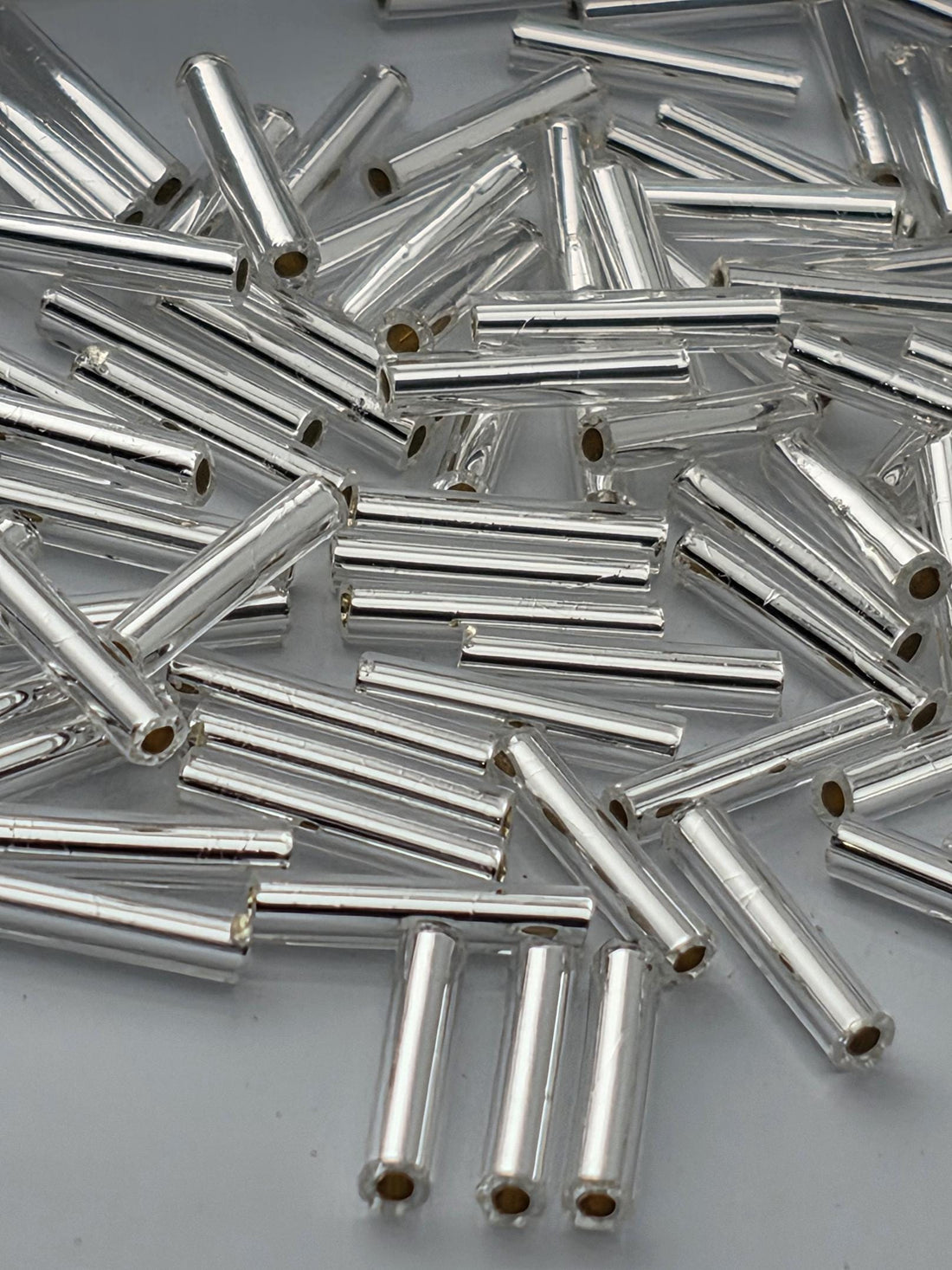 a collection of silver-colored metal rods or tubes scattered on a dark surface.