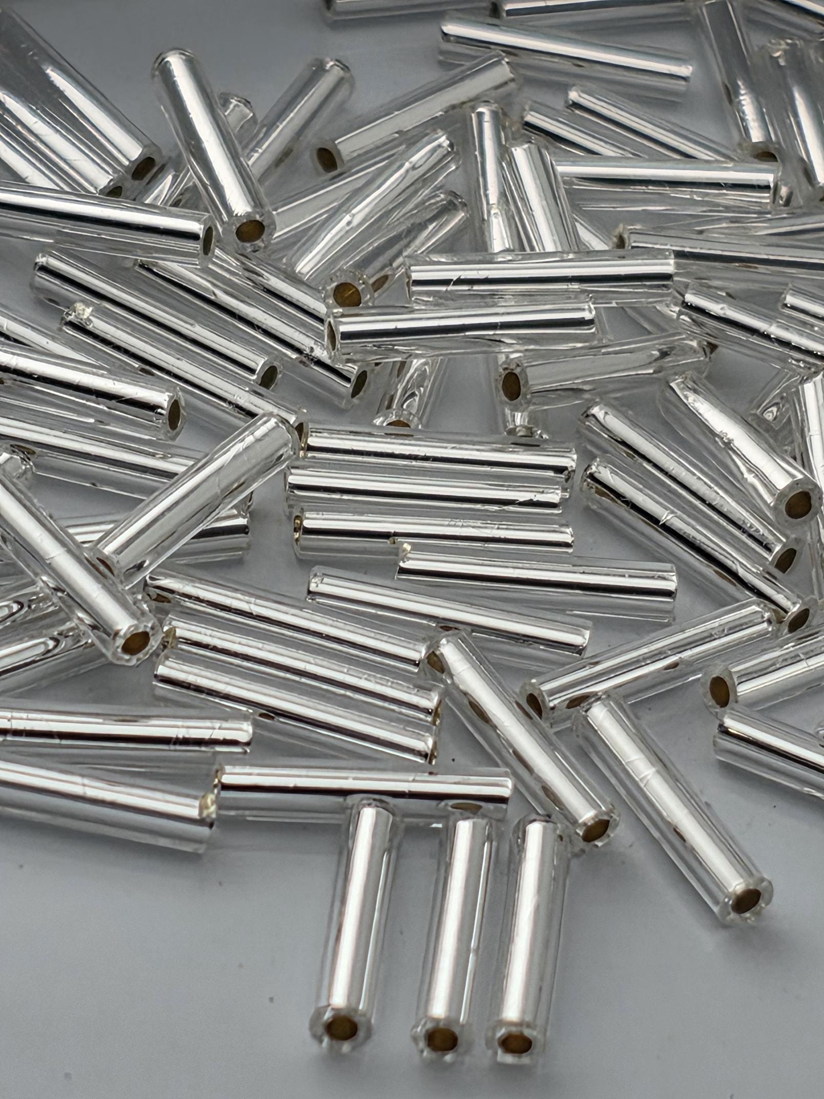 numerous small, cylindrical objects that appear to be made of a shiny, metallic material. The objects are scattered and overlapping, creating a visually interesting and chaotic arrangement.