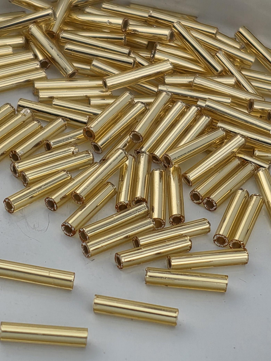 numerous gold-colored metal tubes or rods, which appear to be arranged in a pile or scattered across a surface.