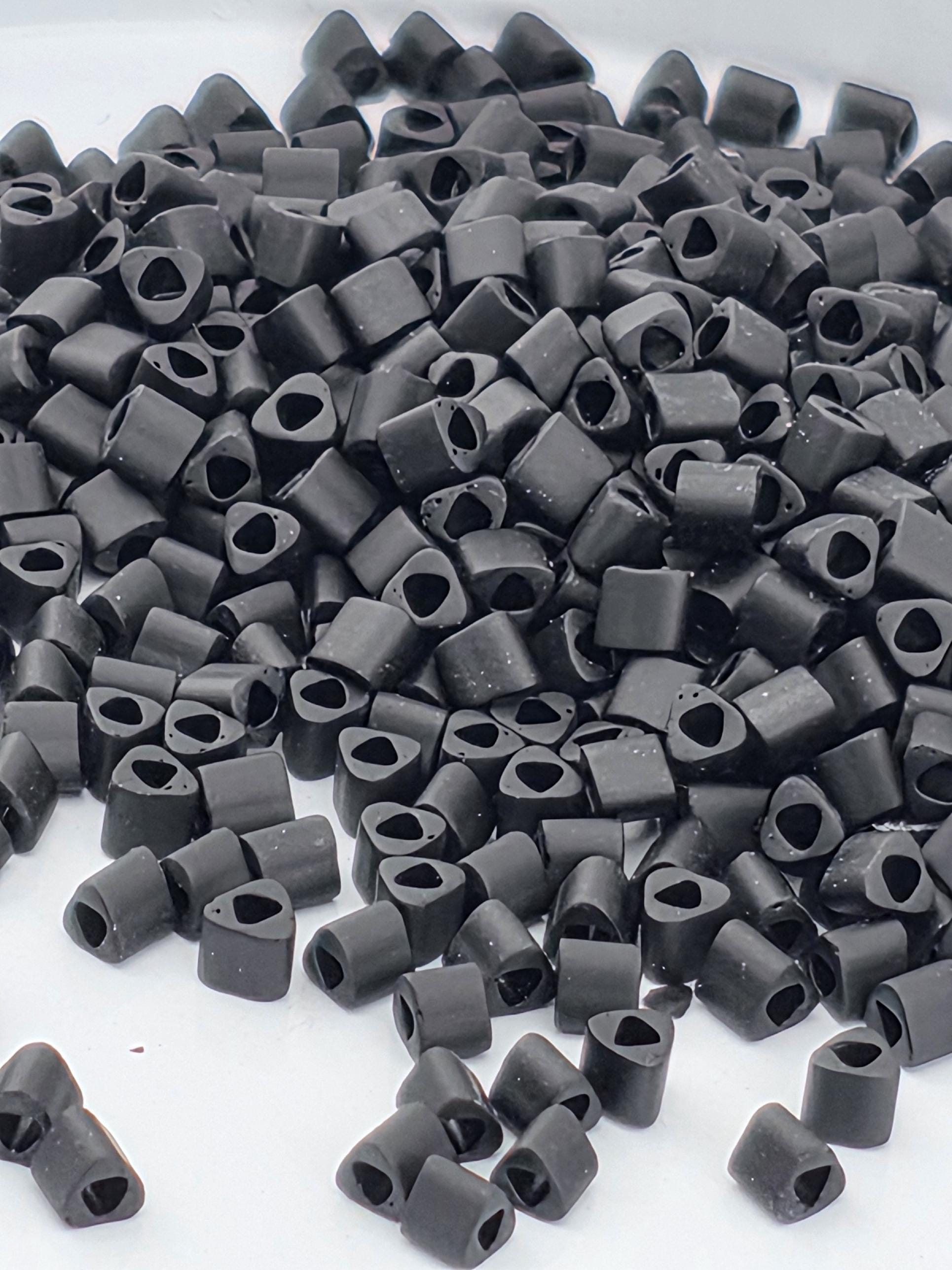 a large pile of small, black objects, possibly beads or small metal pieces, scattered on a white surface.