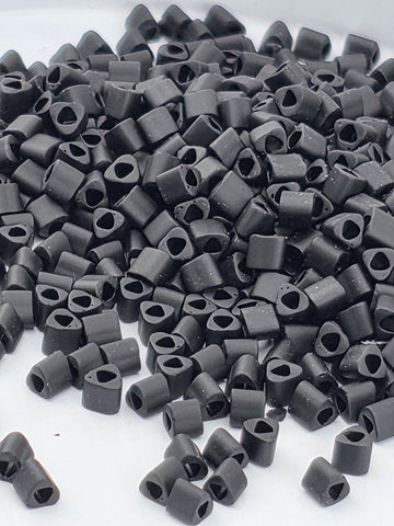 a large pile of small, black objects, possibly beads or small metal pieces, scattered on a white surface.