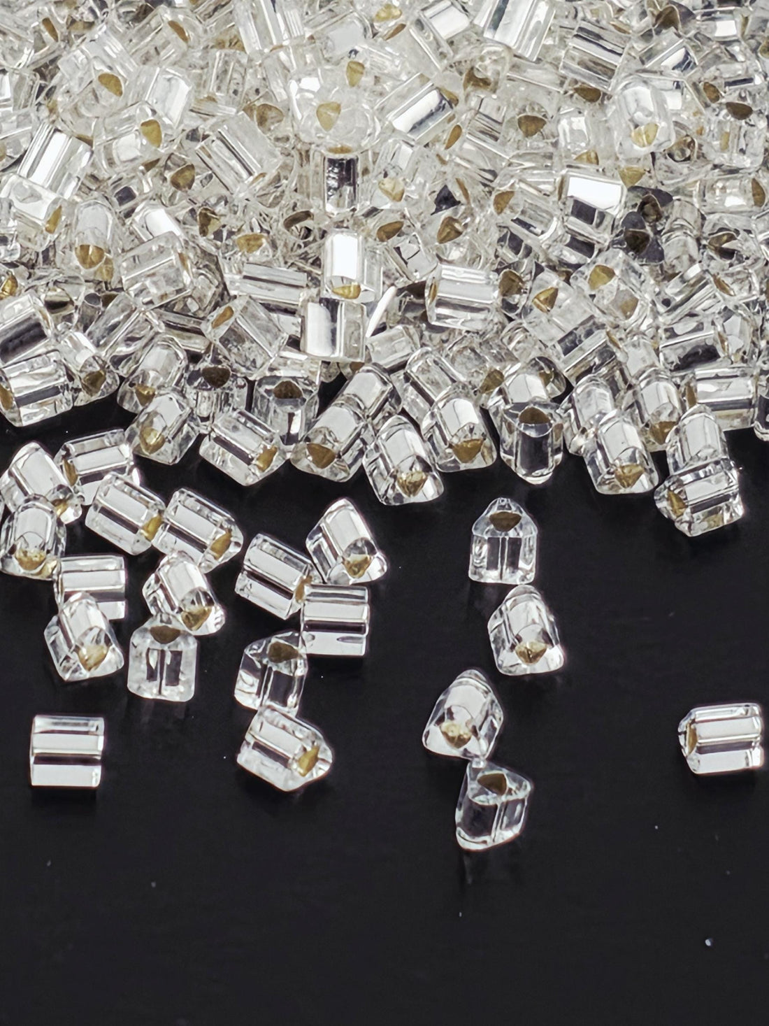 a close-up view of numerous clear, transparent crystal beads scattered across a dark background.