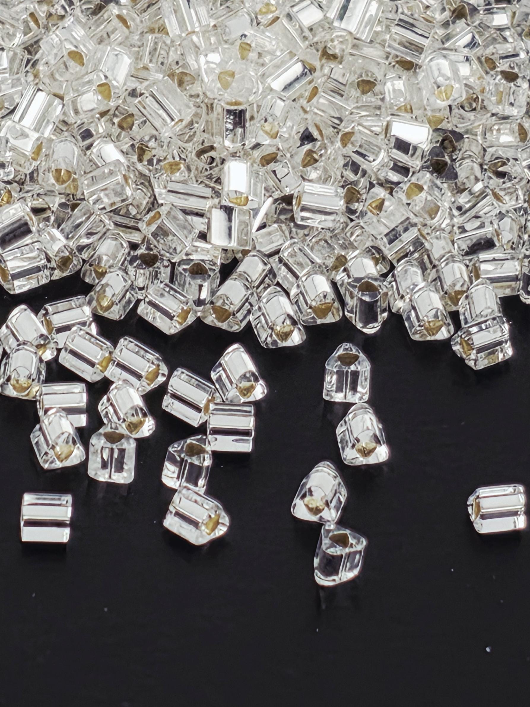 a close-up view of numerous clear, transparent crystal beads scattered across a dark background.