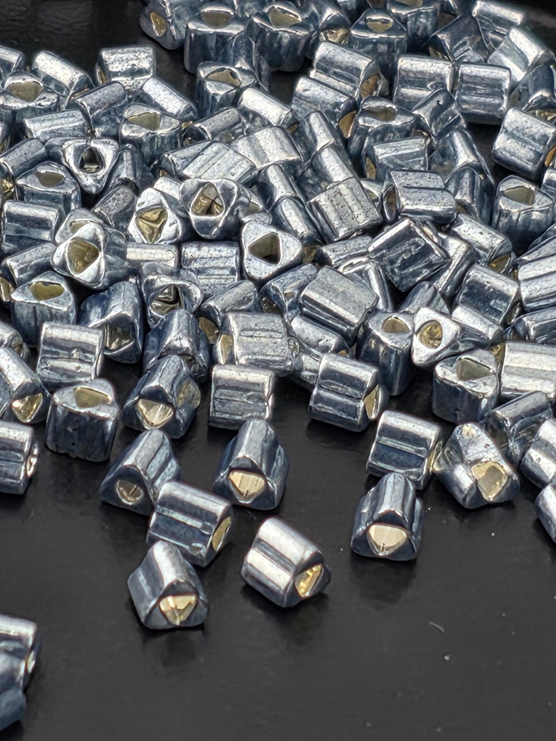 a close-up view of numerous small, metallic beads or pieces scattered on a dark surface.